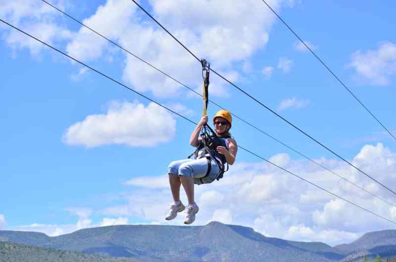 A woman zip lining with the sky in the background