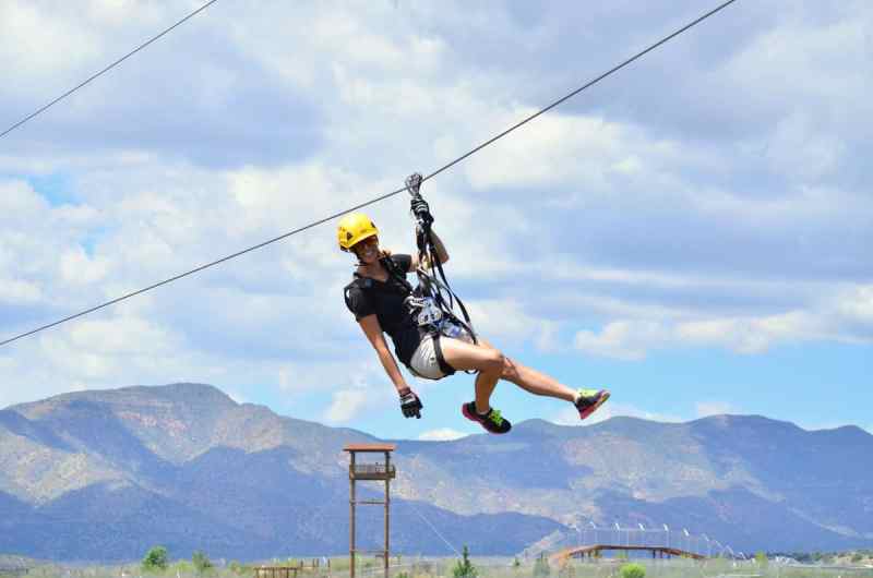 A woman smiling while zip lining with one hand