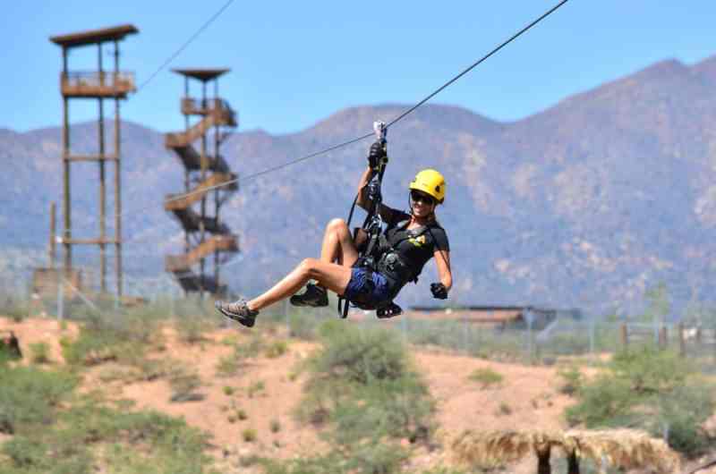 A woman zip lining with the towers behind her