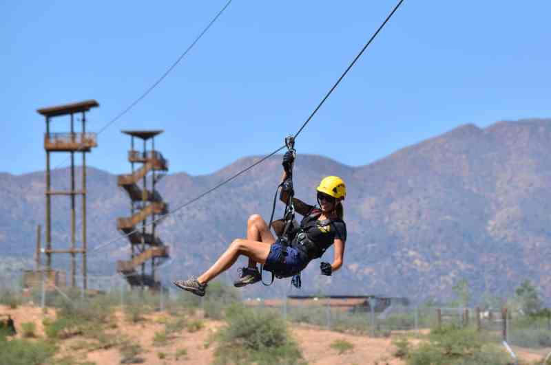 A woman on a zip line with towers behind her