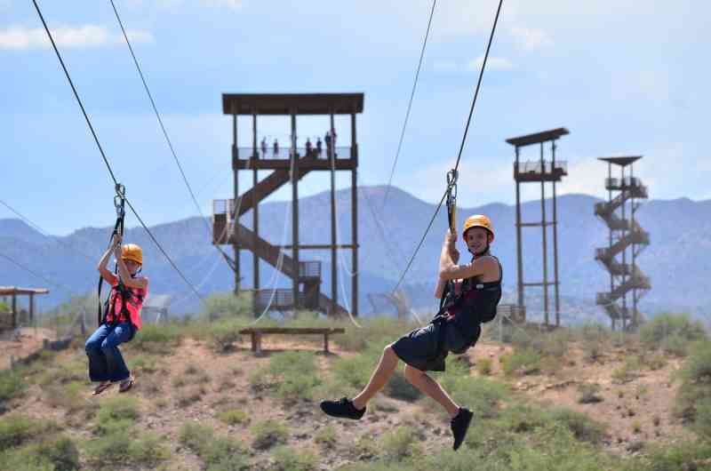 Two siblings zip lining simultaneously