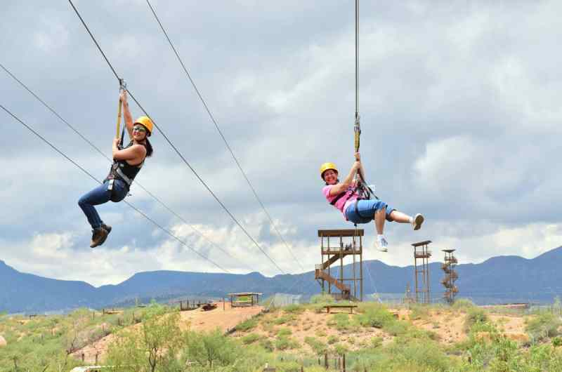 Two women zip lining simultaneously