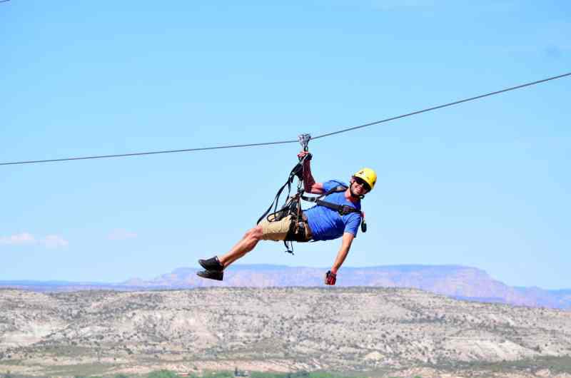 A man holing on with one hand while zip lining