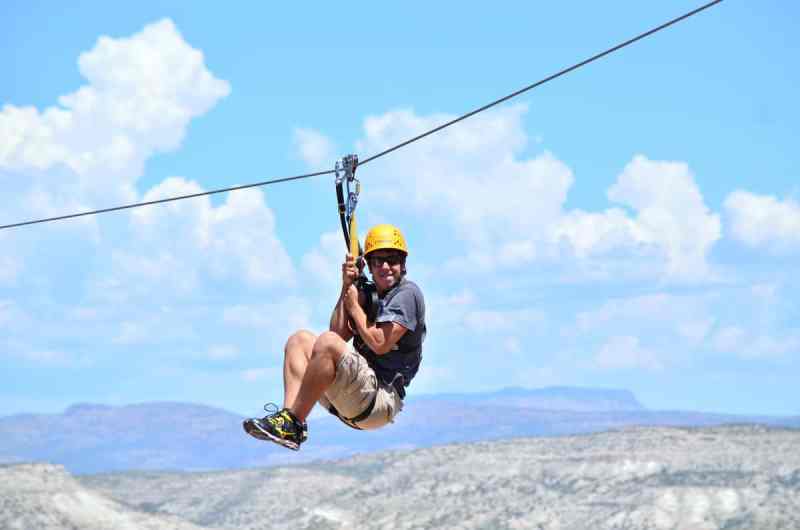 A man holding on tight to to his harness while zip lining