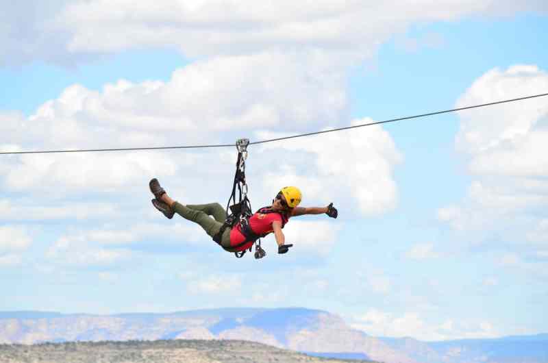 A woman leaning back in her harness on a zip line